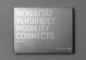 Buch von ThyssenKrupp aus der Corporate Book-Serie mit silber-grau gestreiftem Deckblatt, auf dem in silberner Schrift Mobilität verbindet Mobility Connects steht auf grauem Hintergrund