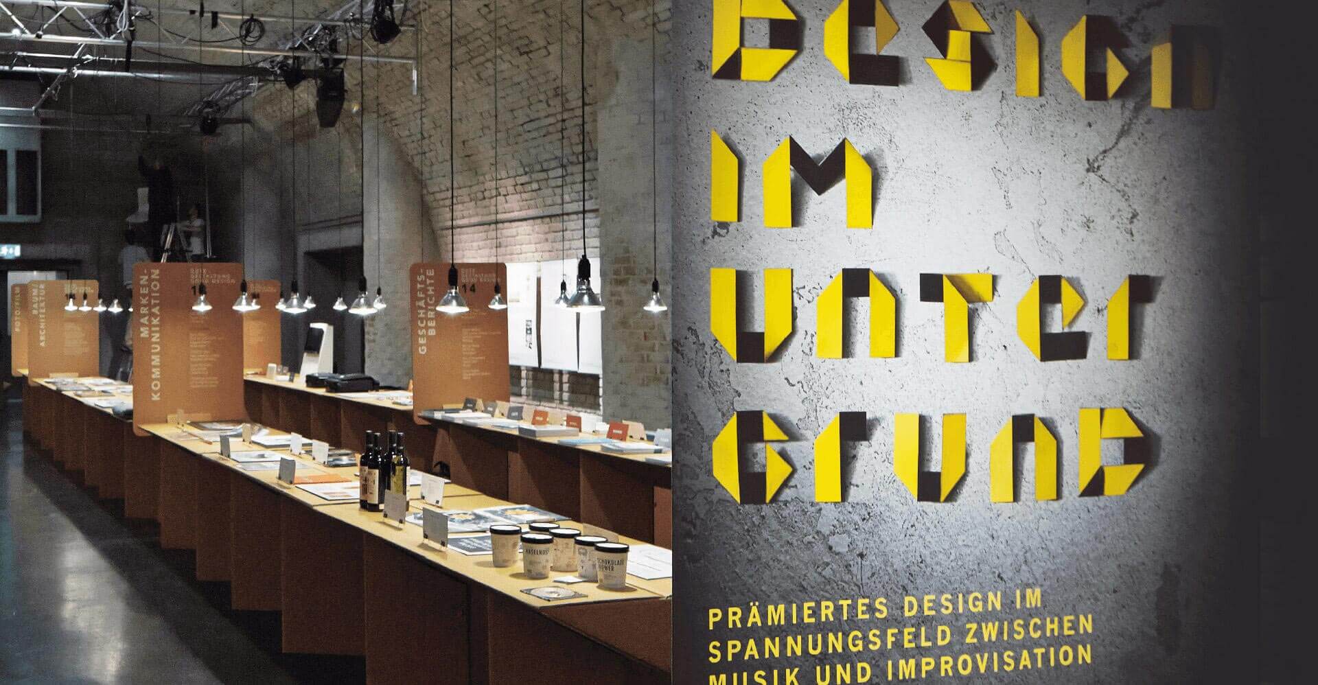 Ausstellungsräumlichkeiten und Plakat mit gelber Schrift von Ausstellungsevent Design im Untergrund