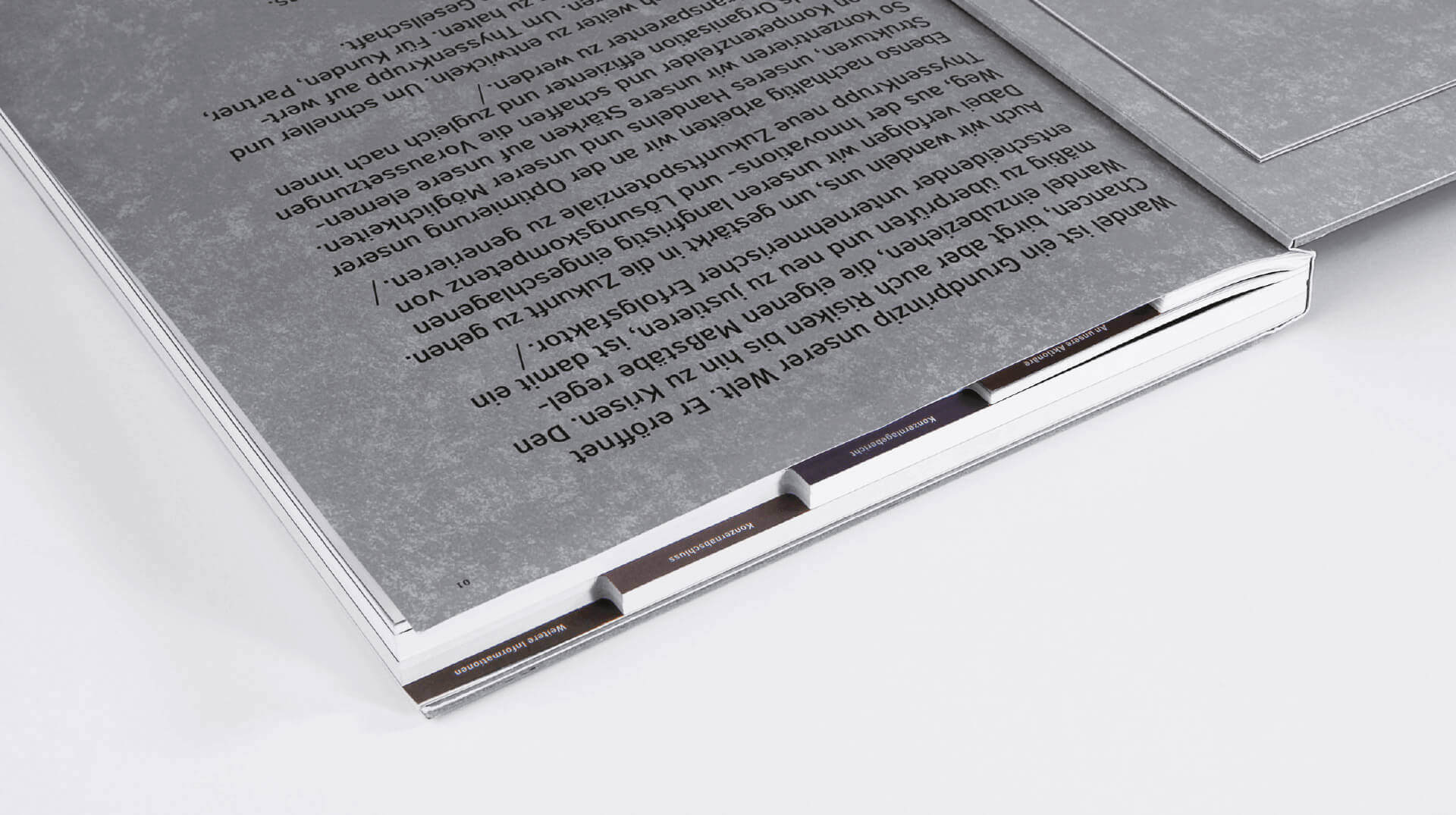 Detail des ThyssenKrupp Geschäftsberichts mit den Kapiteltrennern und Typografie auf silbernem Papier