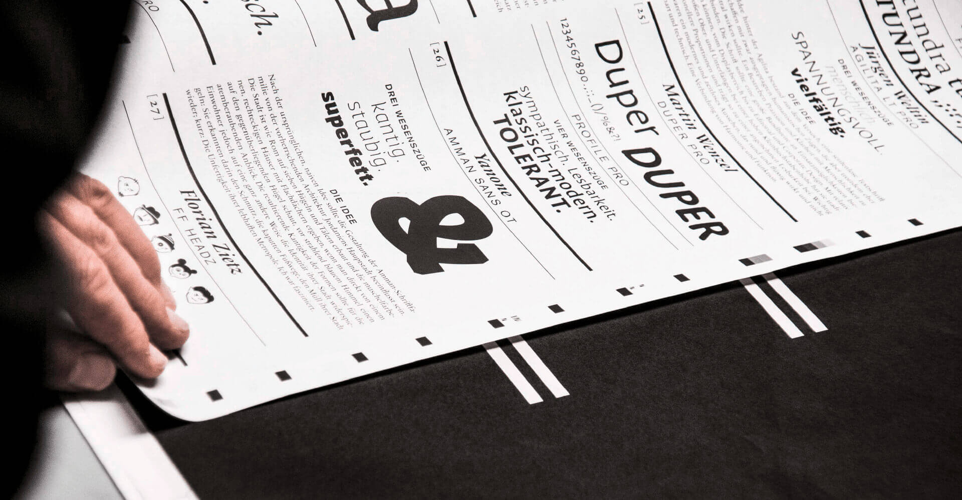 Ausschnitt von Seite des Corporate Book mit viel schwarzer Typografie auf weißem Hintergrund und einer Hand die Blättert