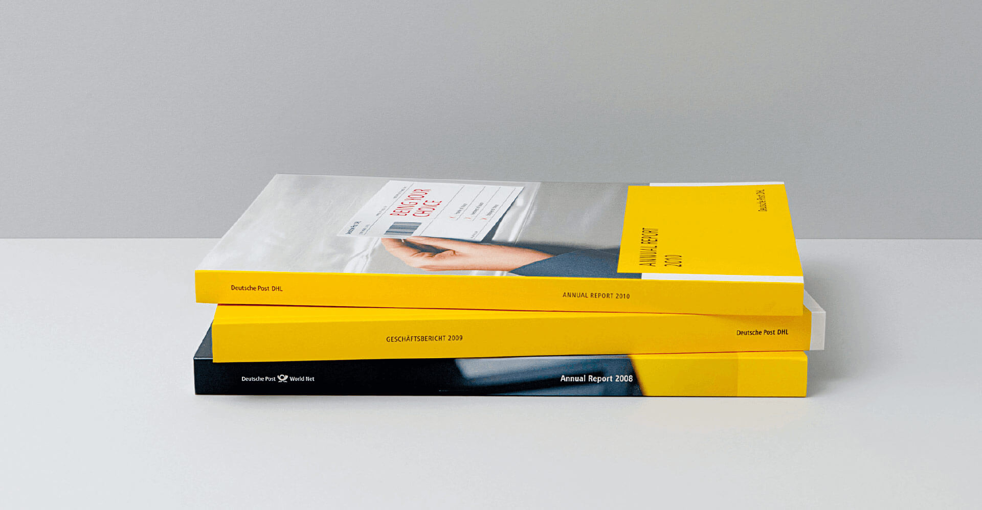 Drei Bücher mit gelbem Rand liegen aufeinander welche den Geschäftsbericht der Deutschen Post enthalten