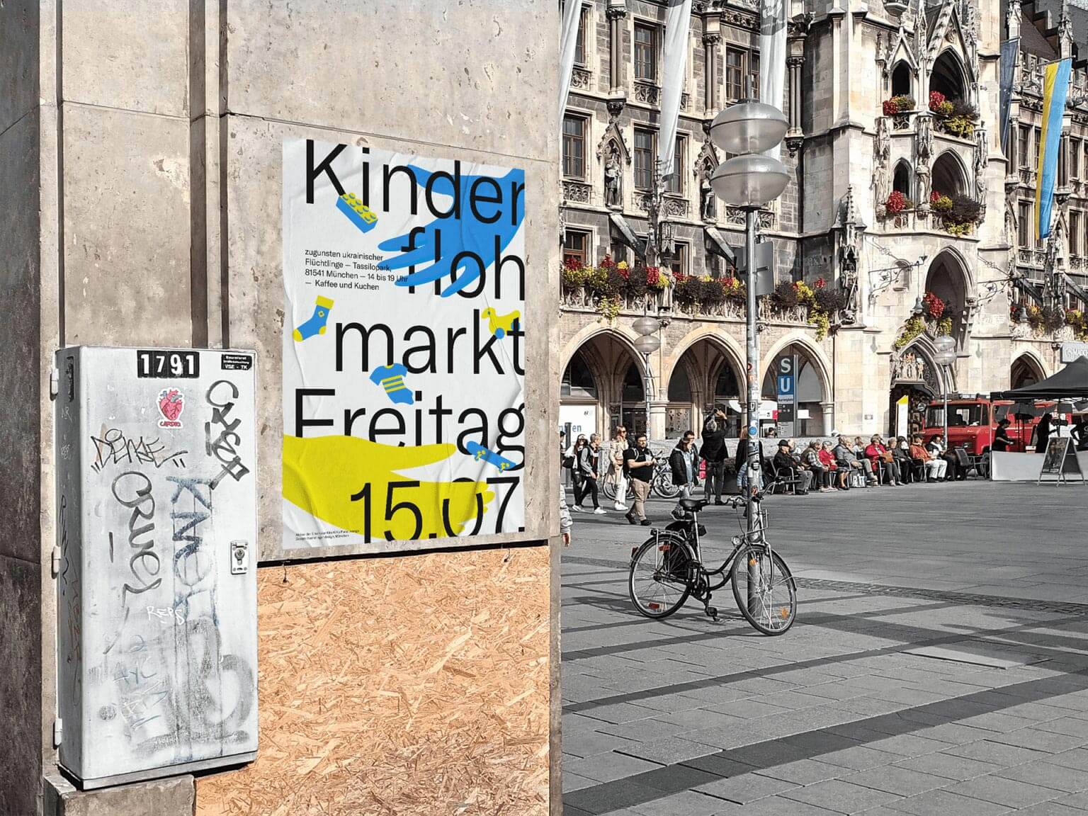 Ein Plakat für einen Kinderflohmarkt mit blau gelben Illustrationen hängt an einer Wand am Marienplatz. Im Hintergrund sind Menschen und ein Fahrrad