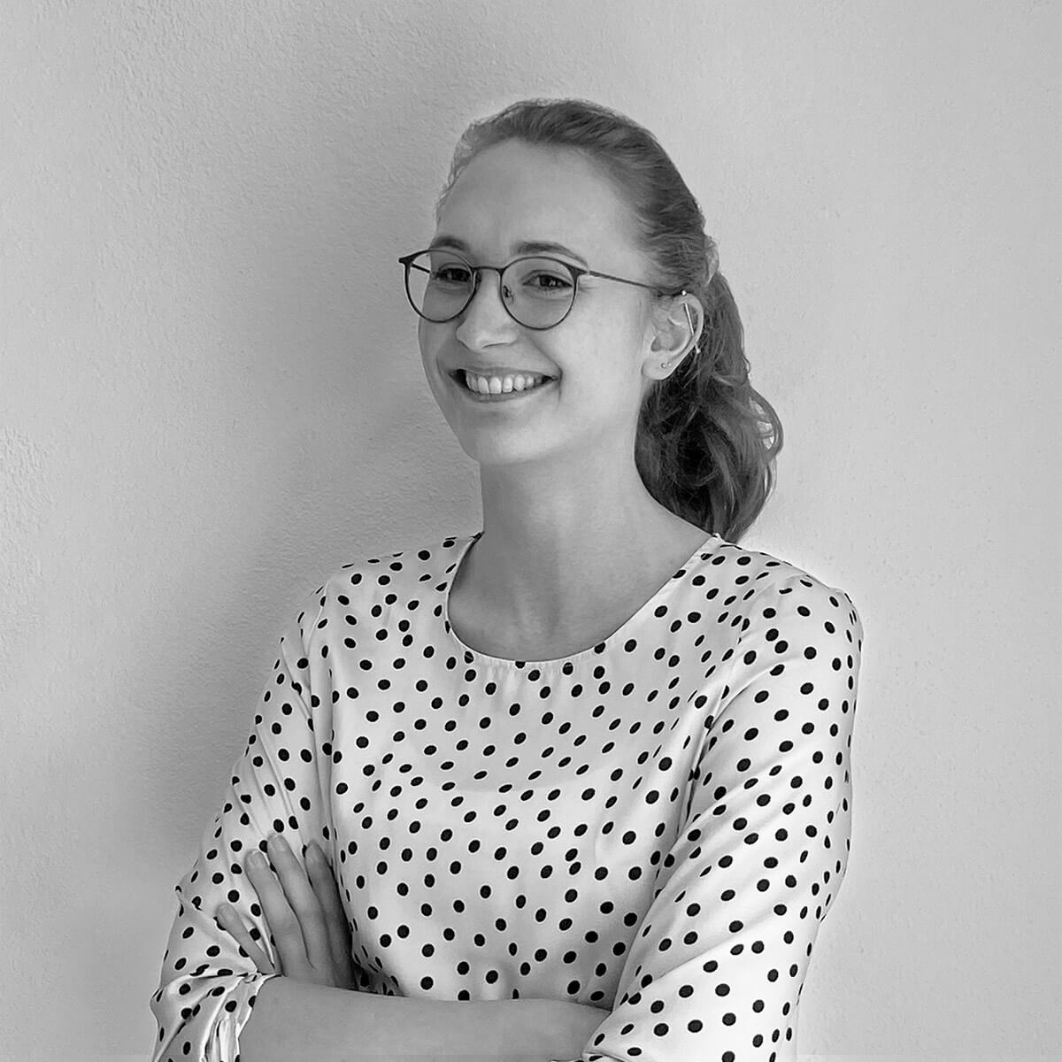 haefelinger design Mitarbeiterin Karina Fuchs lacht und steht vor einer weißen Wand als schwarzweiß Foto