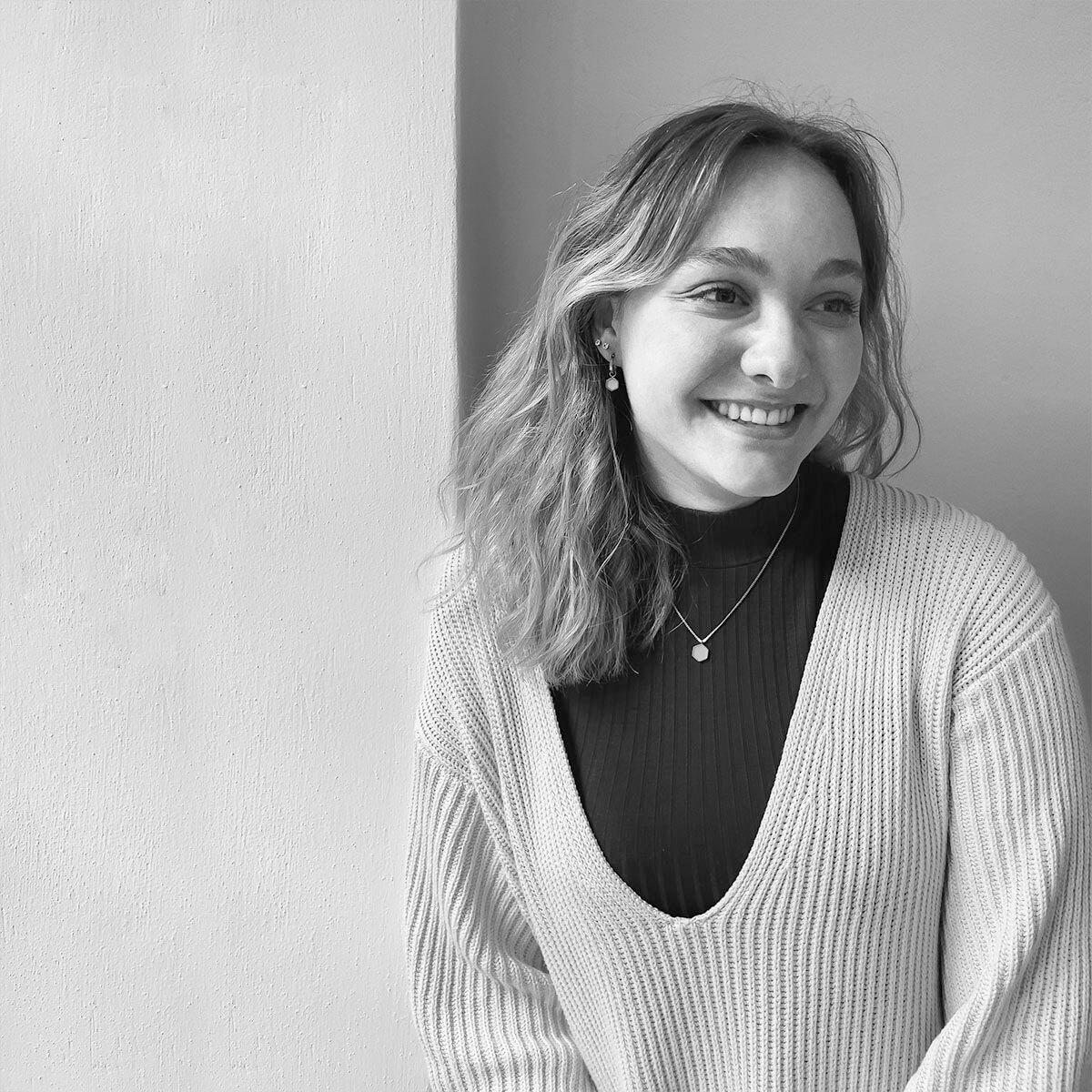 haefelinger design Werkstudentin Ingrid Trojer lacht und steht vor einer weißen Wand als schwarzweiß Foto