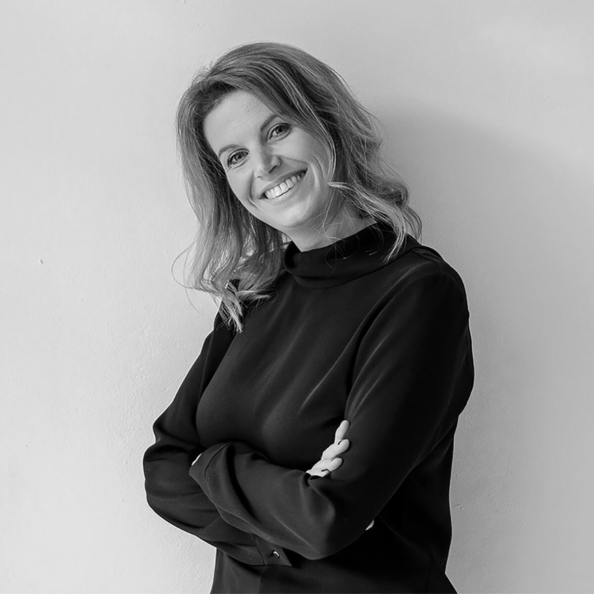 haefelinger design Mitarbeiterin Katharina Kappler lacht und steht vor einer weißen Wand als schwarzweiß Foto